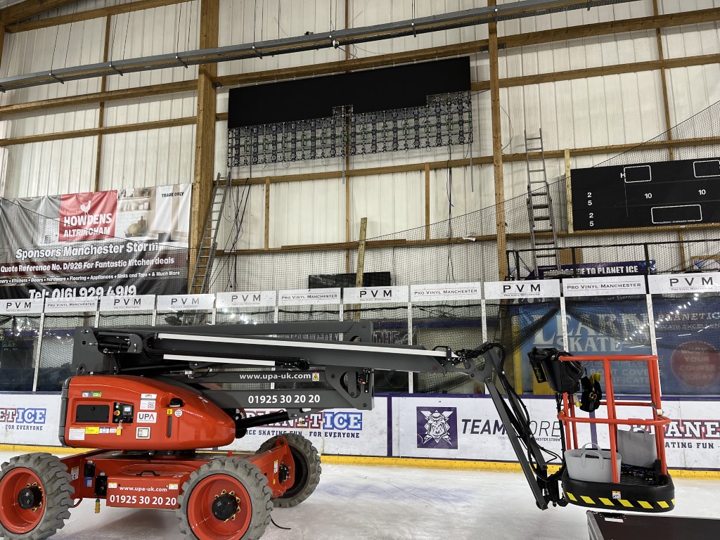 Screen on the wall with half of the screen panels added. Cherry picker lift, used to install, shown in foreground.